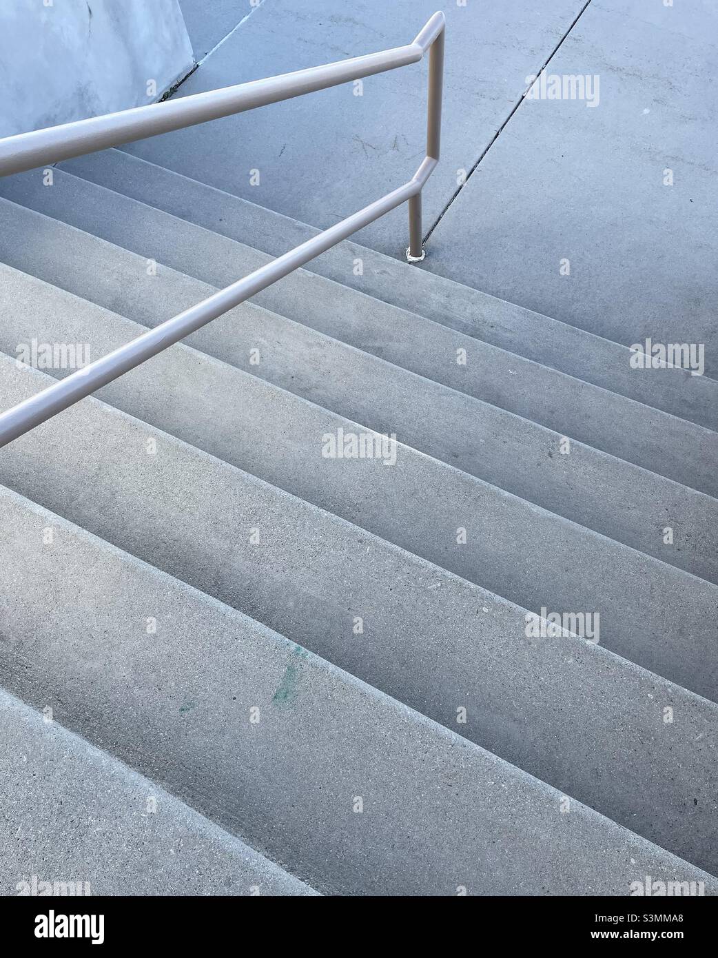 Outdoor cement steps, with a metal handrail in the center, taken at an angle to add some abstract interest. Stock Photo