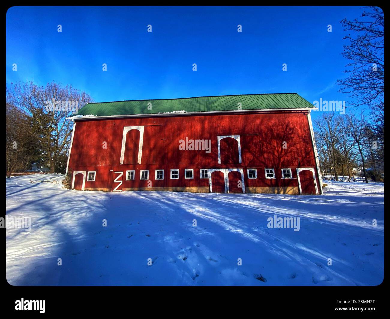A lovely Red barn against the white snow and blue sky Stock Photo