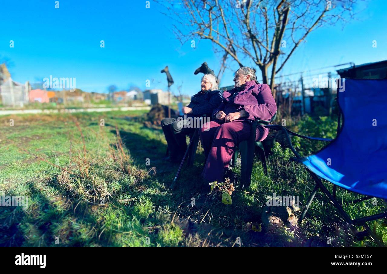 Two senior citizens seated at their allotment. - Smartphone Captured Stock Image