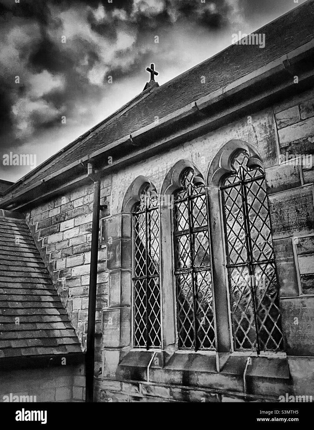 ‘The strength of religion’ a picturesque and quaint village church is juxtaposed by the imminent thunder storm heading its way Stock Photo