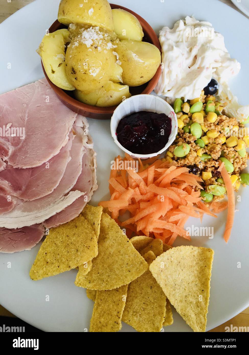 Delicious ham couc cous new potatoes coleslaw and nachos for lunch on the UK Stock Photo