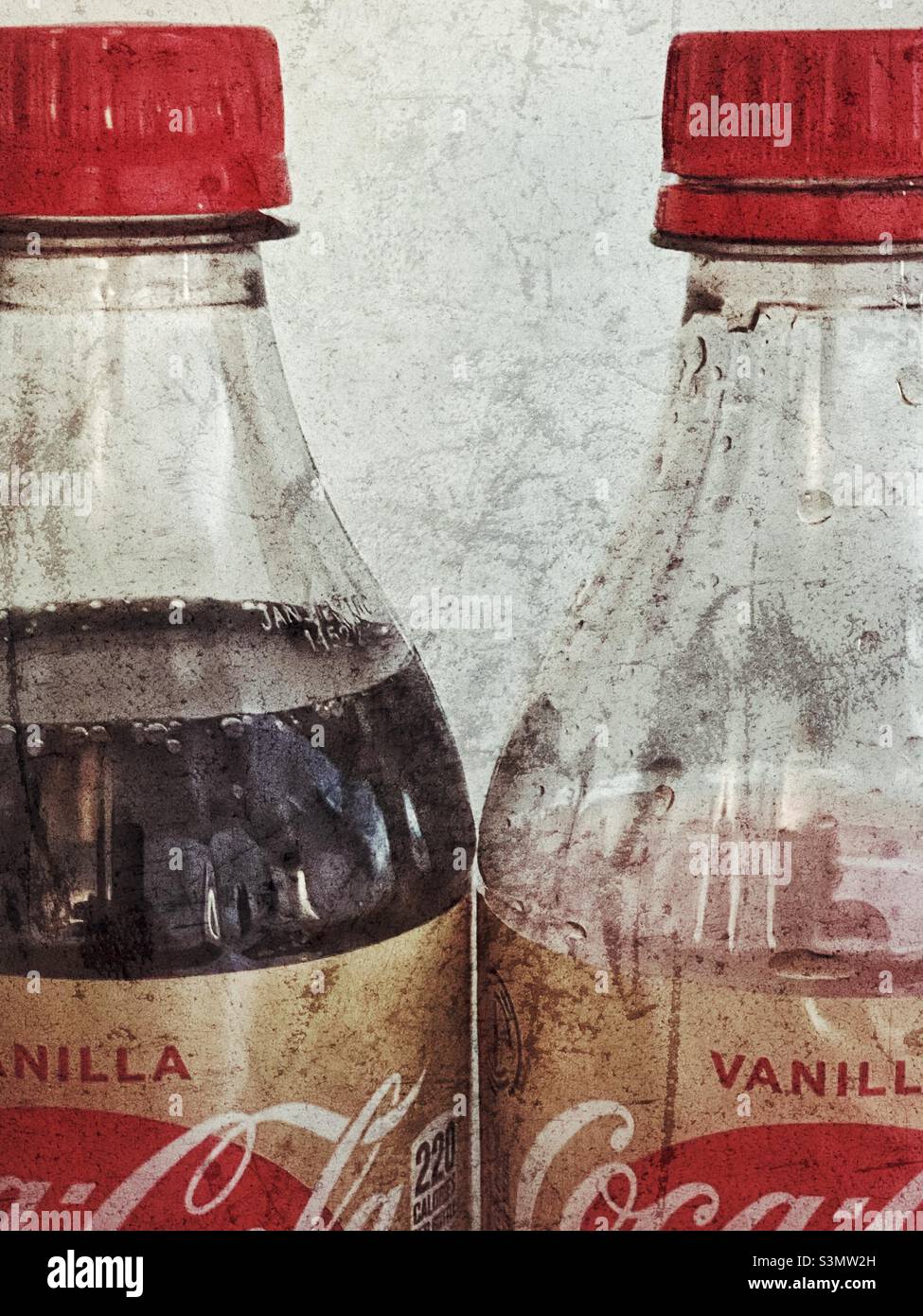 A stylized, with grunge effects, still life of two bottles of Vanilla Coke. One bottle is full while the other has the better part already consumed. - Smartphone Captured Stock Image
