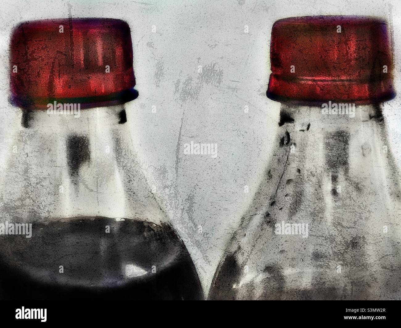 A stylized, with grunge effects, still life of two bottles of Vanilla Coke. One bottle is full while the other has the better part already consumed. - Smartphone Captured Stock Image