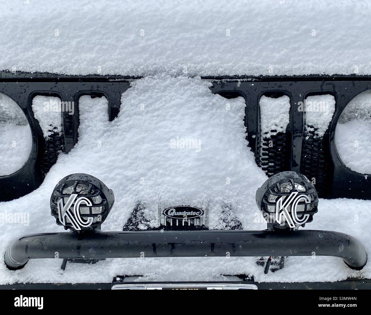 Snow covering the front of a black Jeep Wrangler with winch and off-road lights Stock Photo