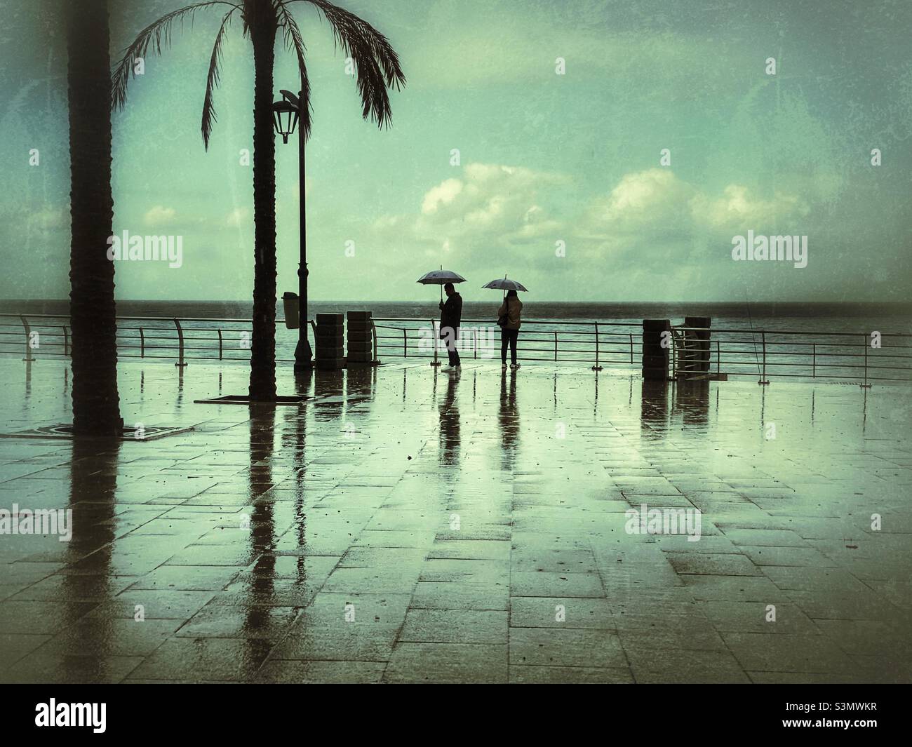 Couples with umbrella standing at the Mediterranean Sea Beirut Lebanon promenade in a rainy day Stock Photo