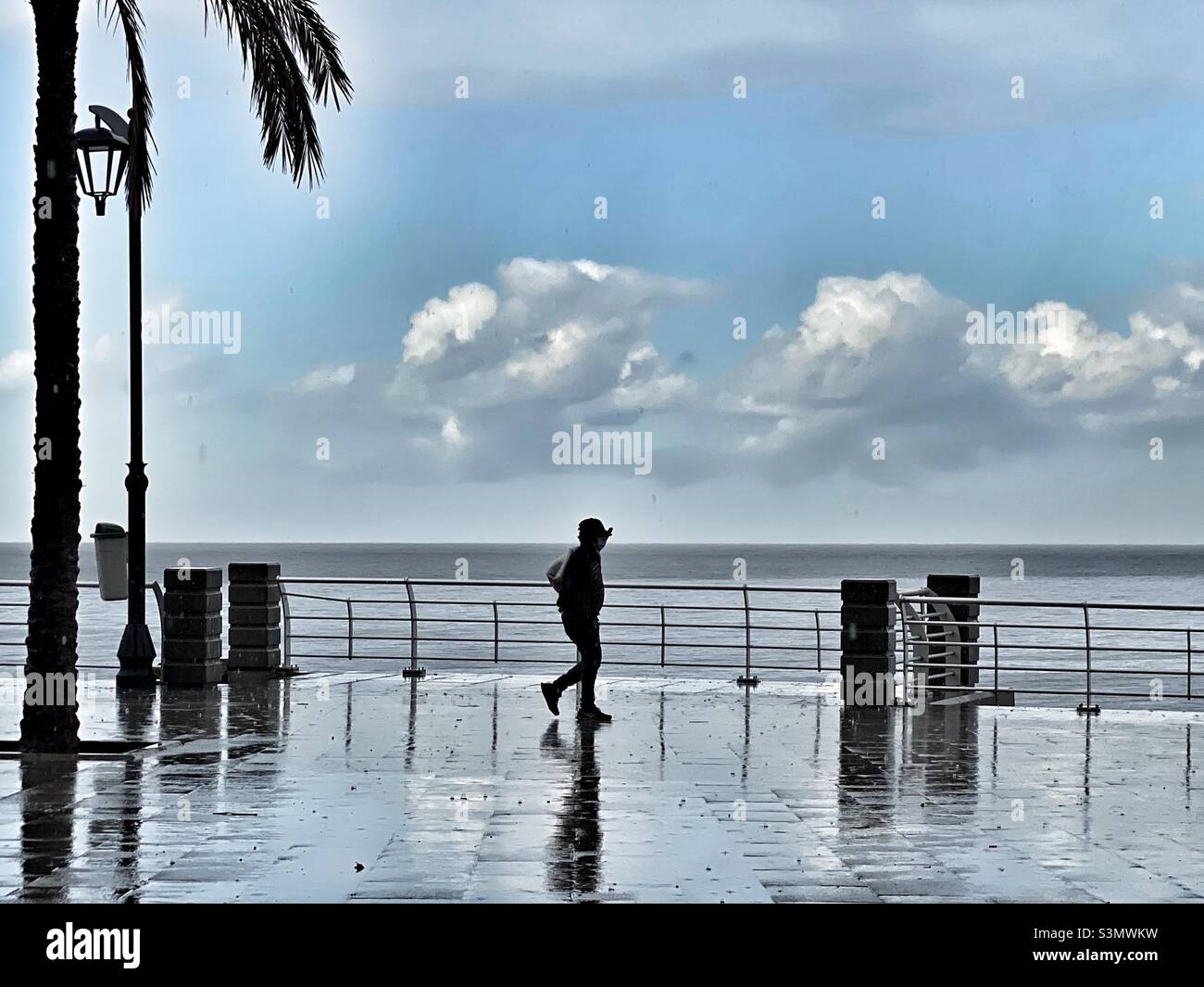 Adult waking under the rain at the sea promenade Stock Photo