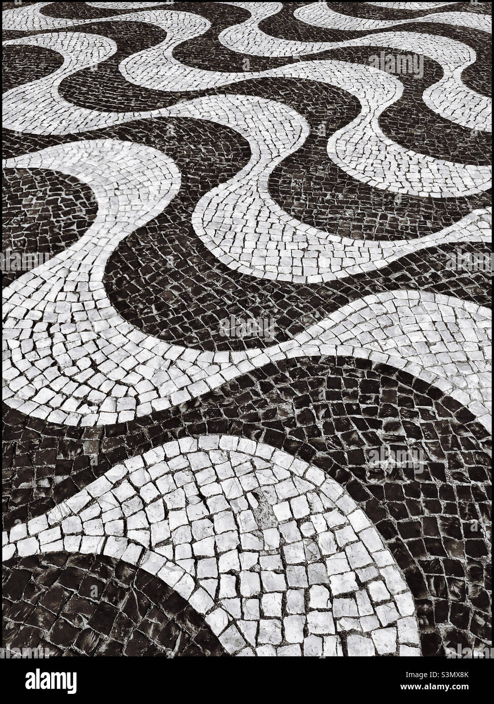Wavy lines and symmetrical shapes created by small tiles in an outdoor pavement area. Creative? Interesting? Thought provoking? Atmospheric? Artistic? Rubbish? Photo ©️ COLIN HOSKINS. - Smartphone Captured Stock Image