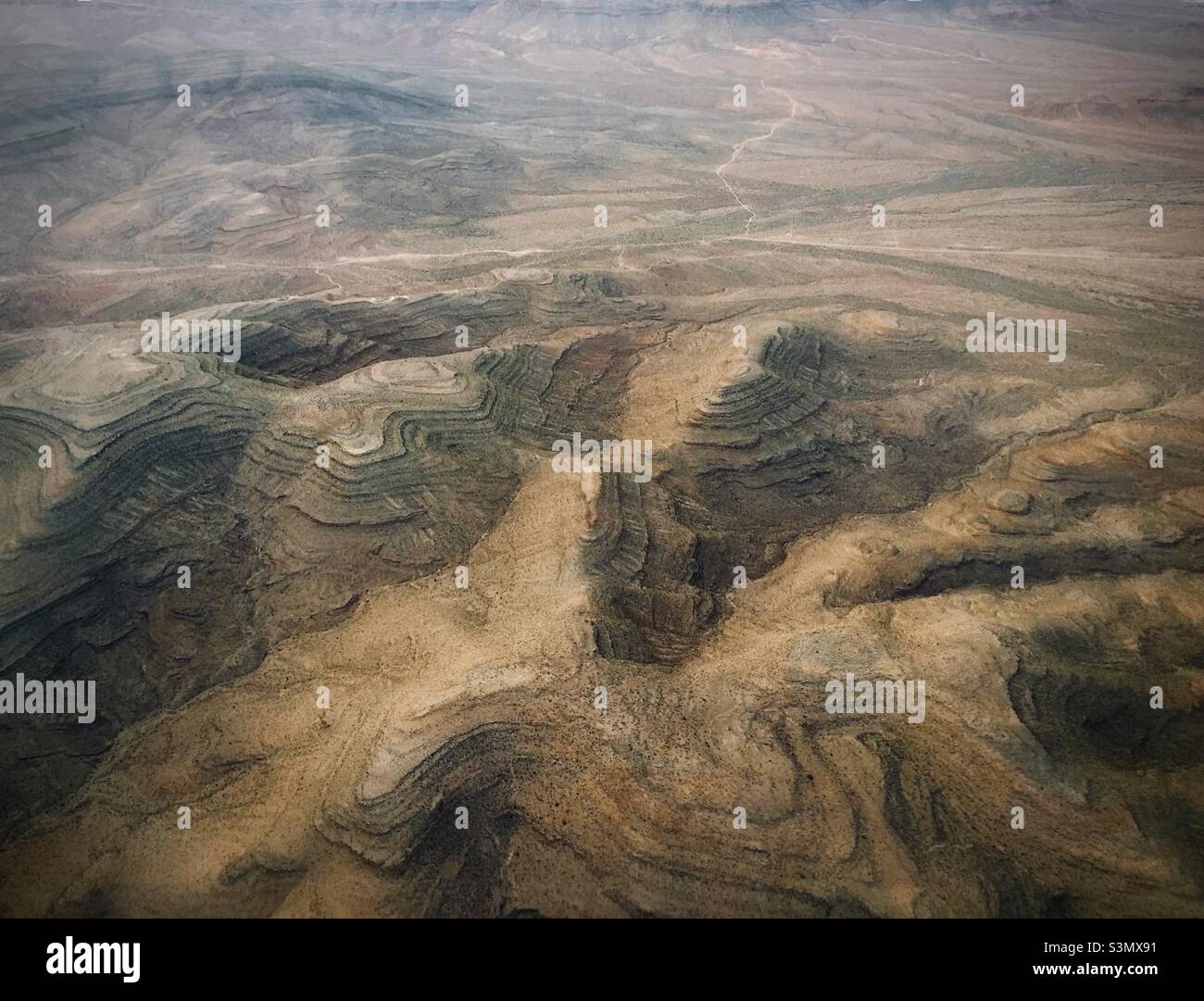 Aerial shot, taken from a plane from Las Vegas to Los Angles. Deep valleys and mountains appear like an the landscape from another plant. Stock Photo