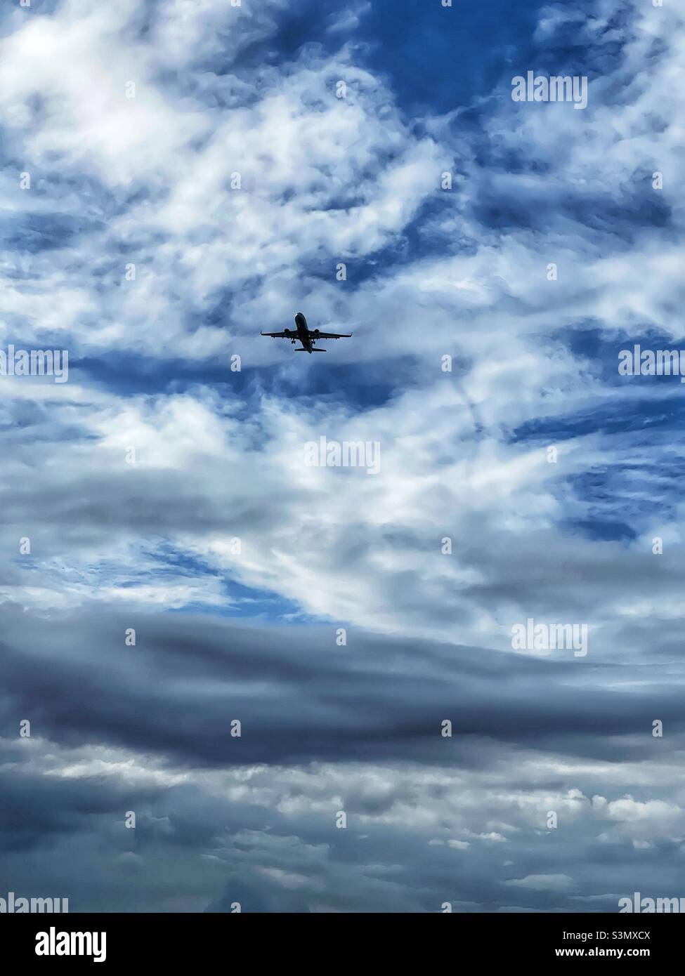 Passenger jet airplane against blue sky with clouds - Smartphone Captured Stock Image