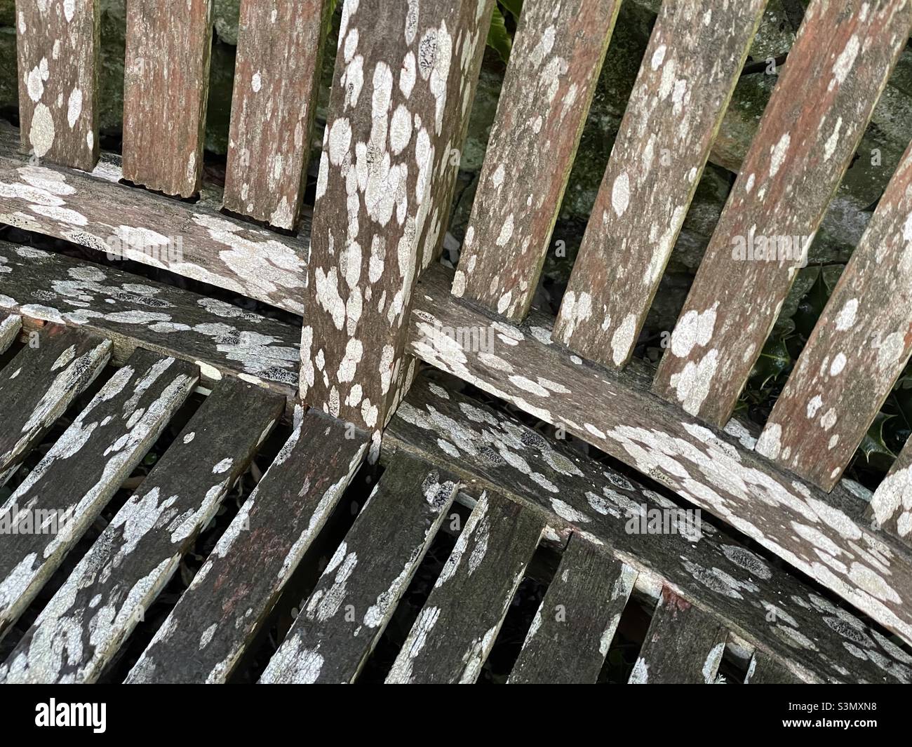 A detail of an old garden seat, the slats weathered and marked with lichen - Smartphone Captured Stock Image
