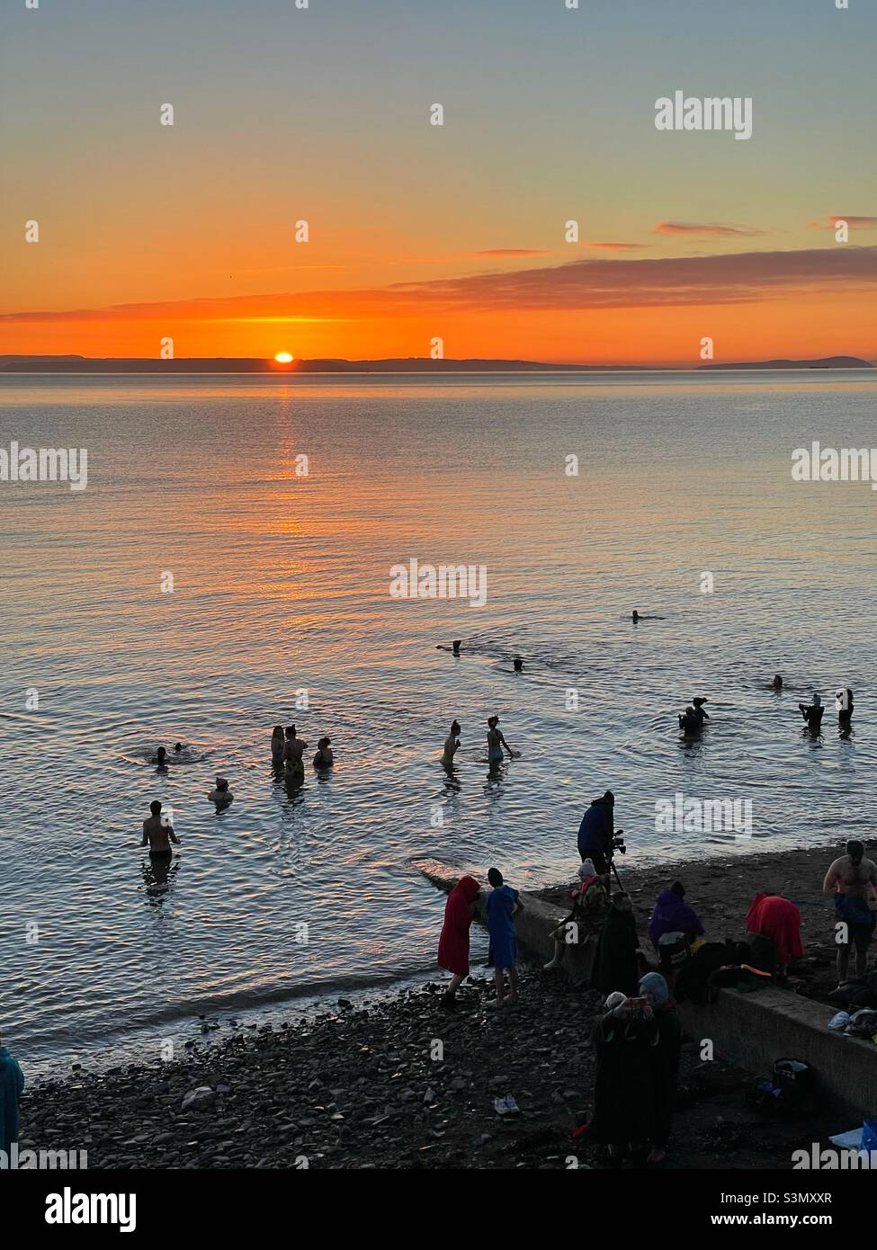Cold water swimmers on Penarth sea front, South Wales, at sunrise, mid January. Stock Photo