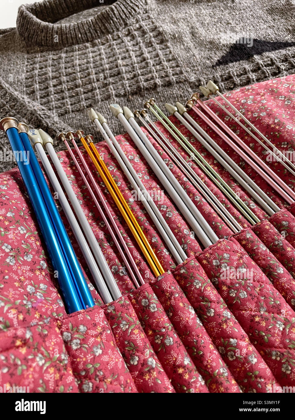 Close up of a knitting needle organizer and finished gray sweater, 2022, United States - Smartphone Captured Stock Image