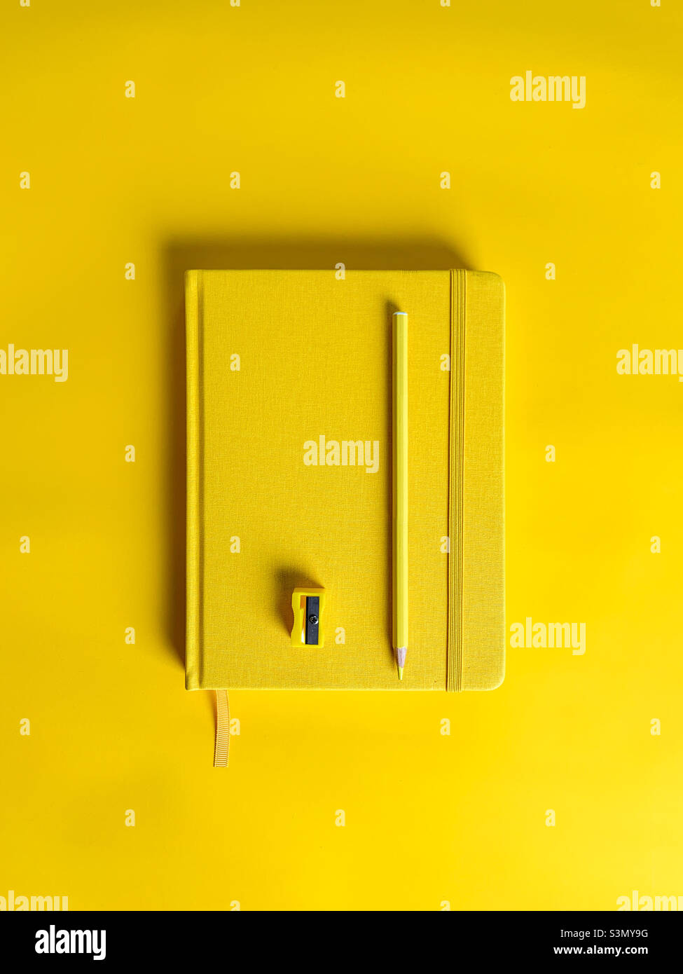 Office workplace with yellow notepad, pencil and sharpener - Smartphone Captured Stock Image