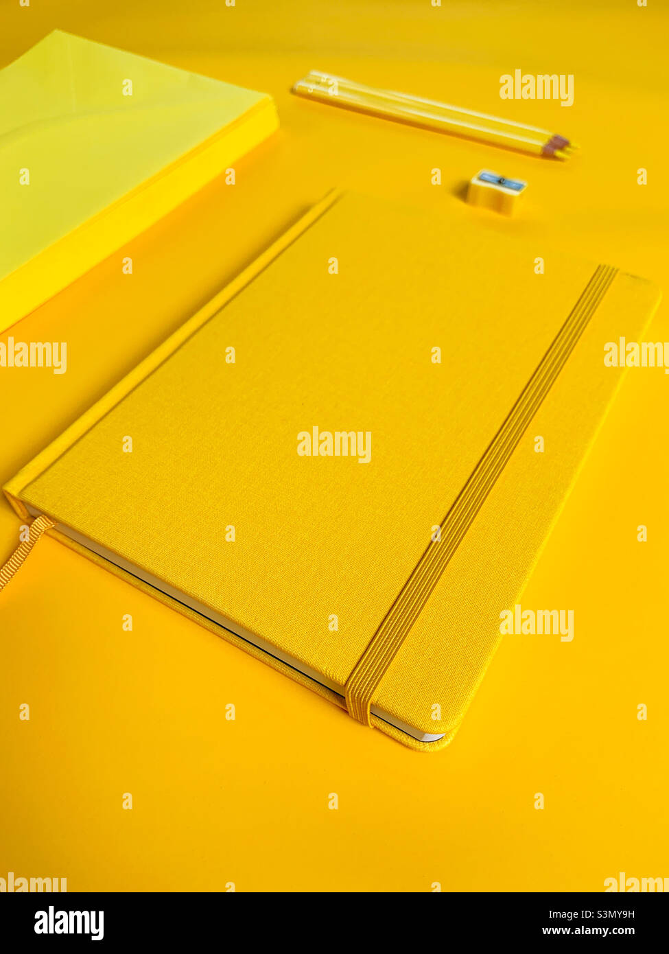 Office workplace with yellow notepad, pencil’s, envelopes and sharpener - Smartphone Captured Stock Image