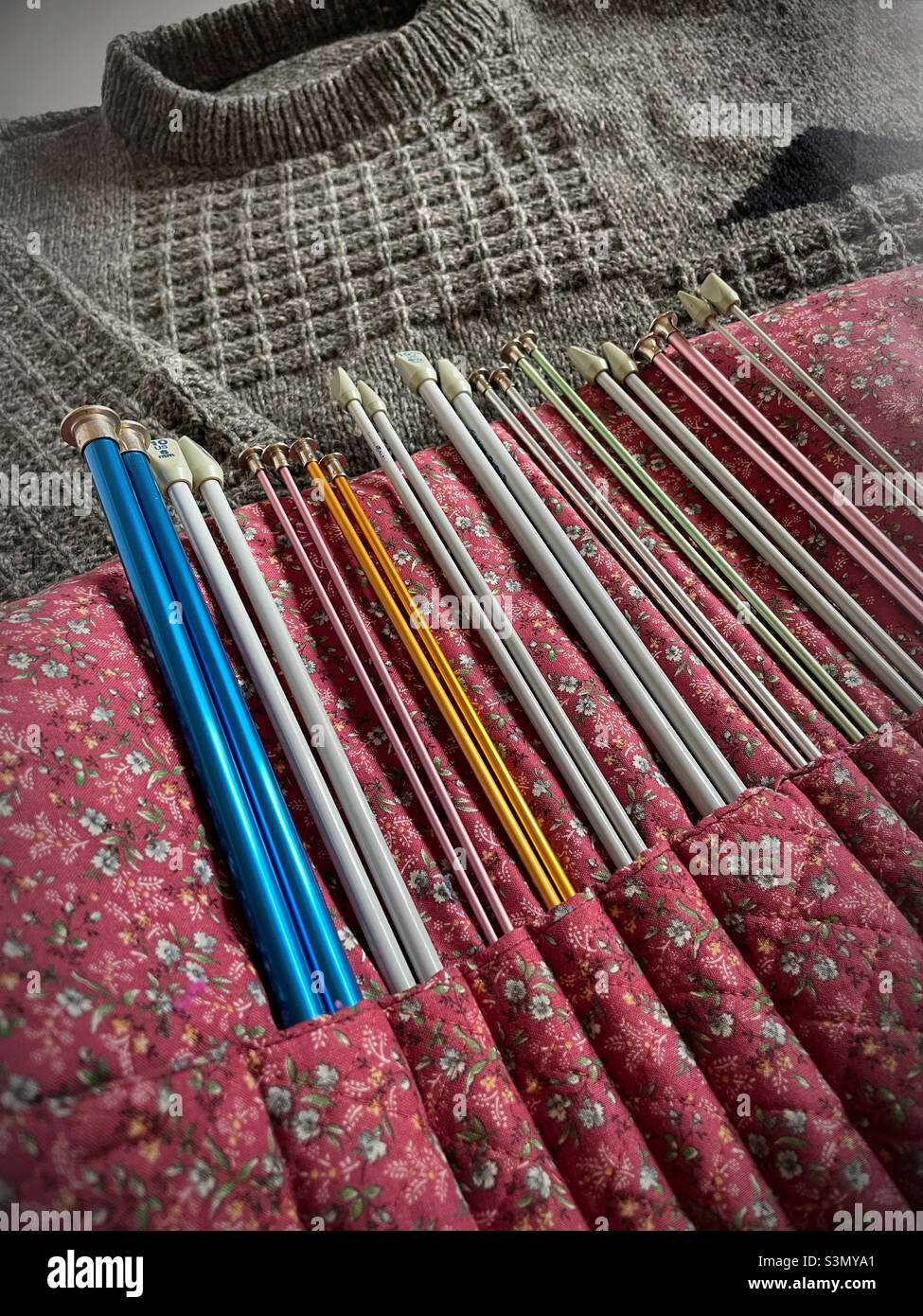 Still life of a knitting needle organizer and finished gray sweater, 2022, United States - Smartphone Captured Stock Image