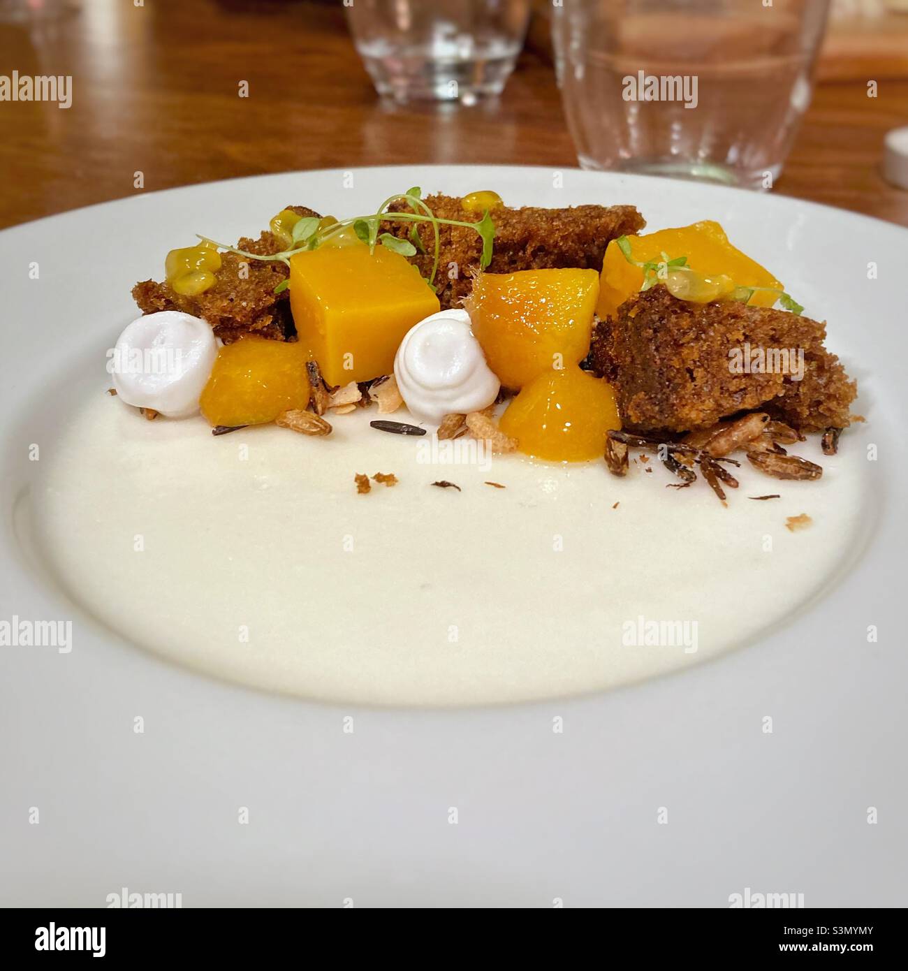 Coconut panna cotta dessert with mango and passion fruit on a white dish - Smartphone Captured Stock Image