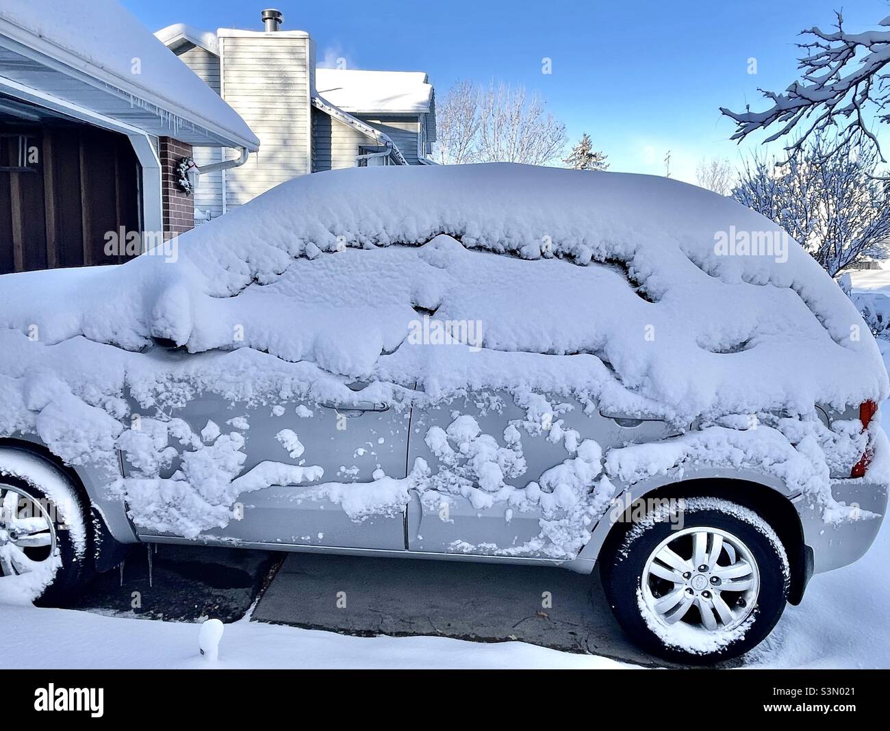 Morning after a heavy snowstorm drops a foot of snowfall in Utah, USA. This SUV was outside in a home’s driveway and is caked with the blowing snow from the night before. - Smartphone Captured Stock Image