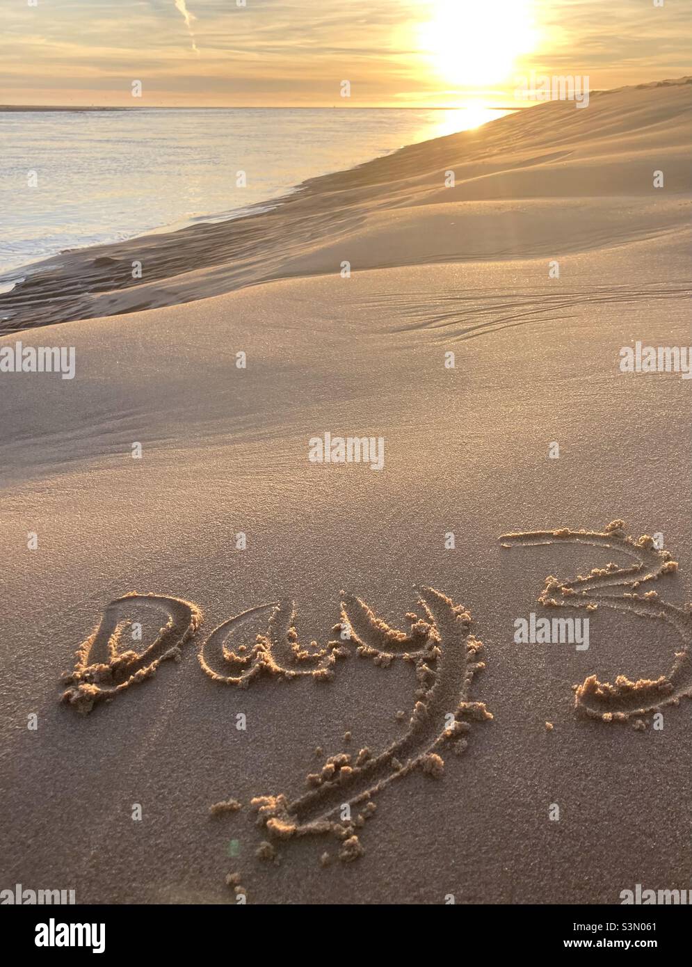Day 3 written in the sand at sunrise Stock Photo
