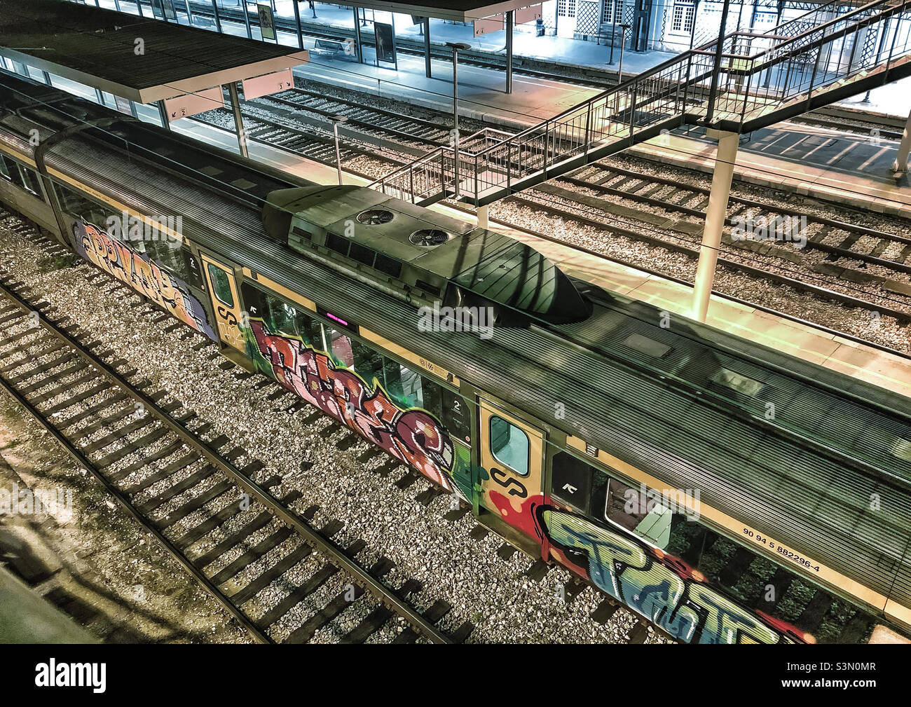 A view from above a railway station with several tracks and platforms, with graffitied train carriages - Smartphone Captured Stock Image