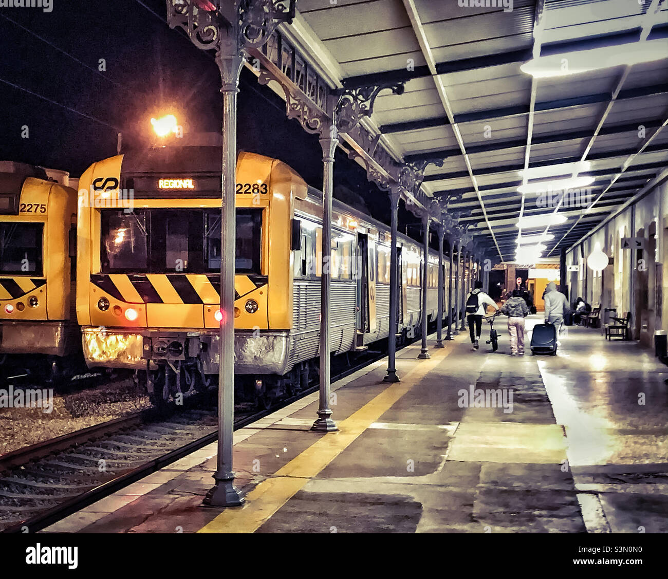 People with luggage walk along the platform aside a waiting train Stock Photo