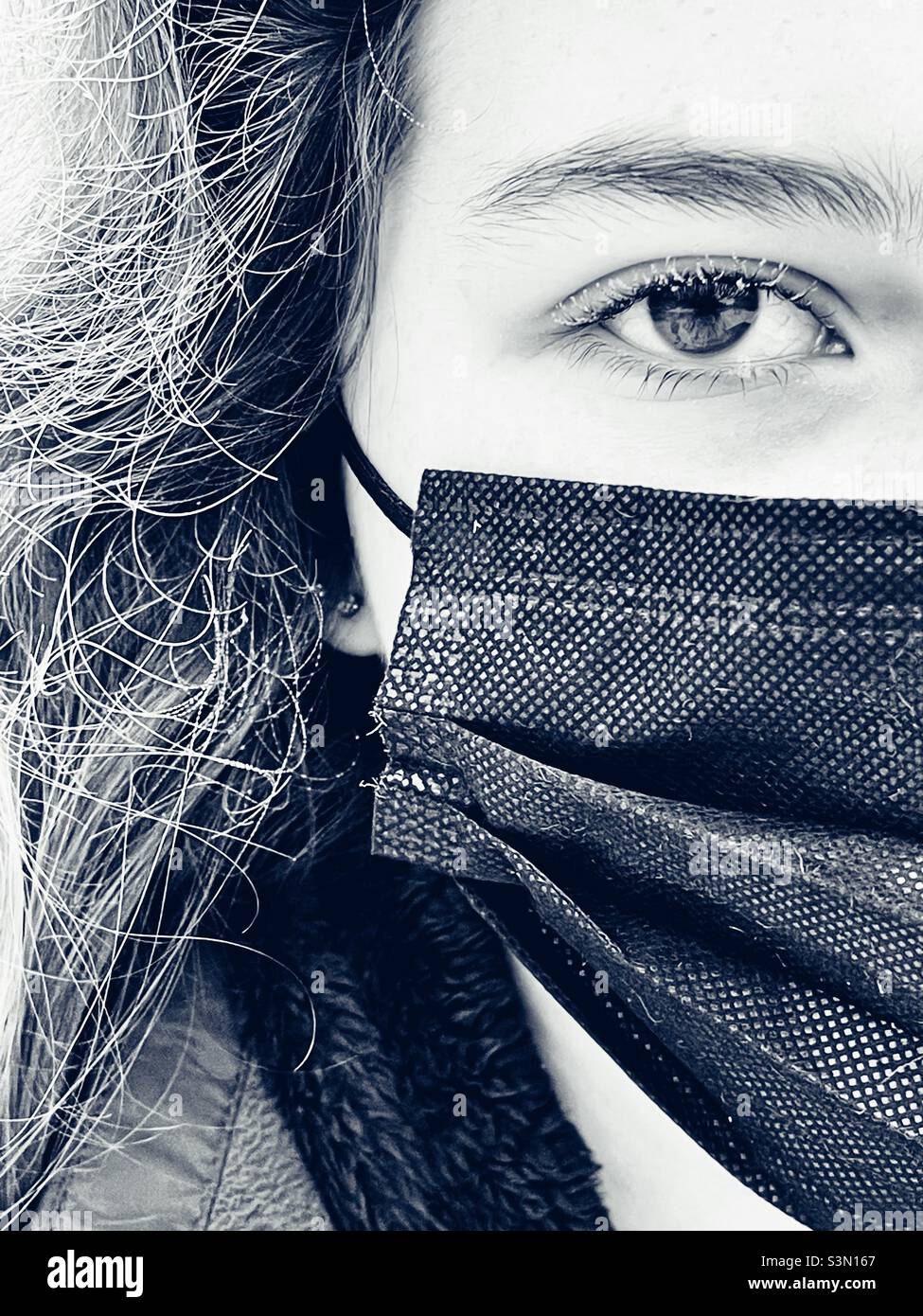 Closeup portrait of teenage girl wearing medical mask with frost on eyelashes and hair Stock Photo