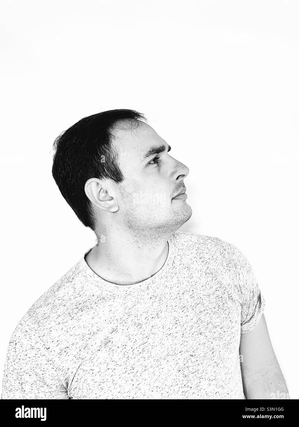 Profile of young man with a reflective gesture. Thoughtful. Considering options. - Smartphone Captured Stock Image