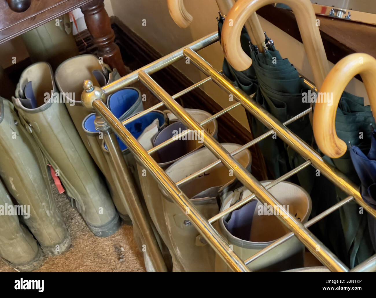 An umbrella stand in the porch of a Rutland country house hotel with umbrellas and Wellington boots, available for use by the guests - Smartphone Captured Stock Image