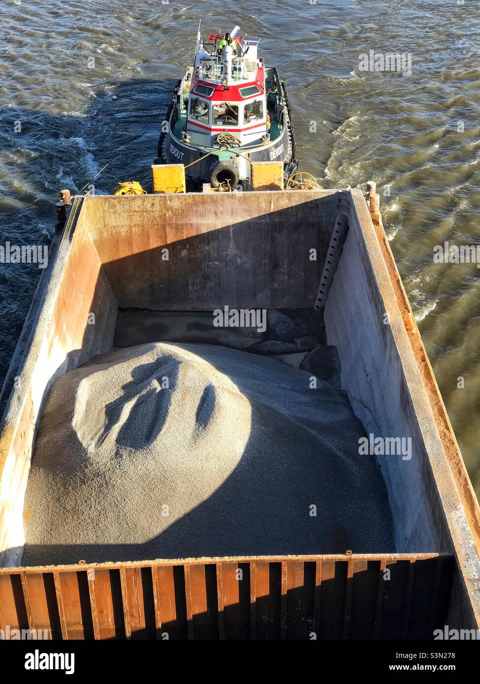 A container barge of building materials being transported by tugboat