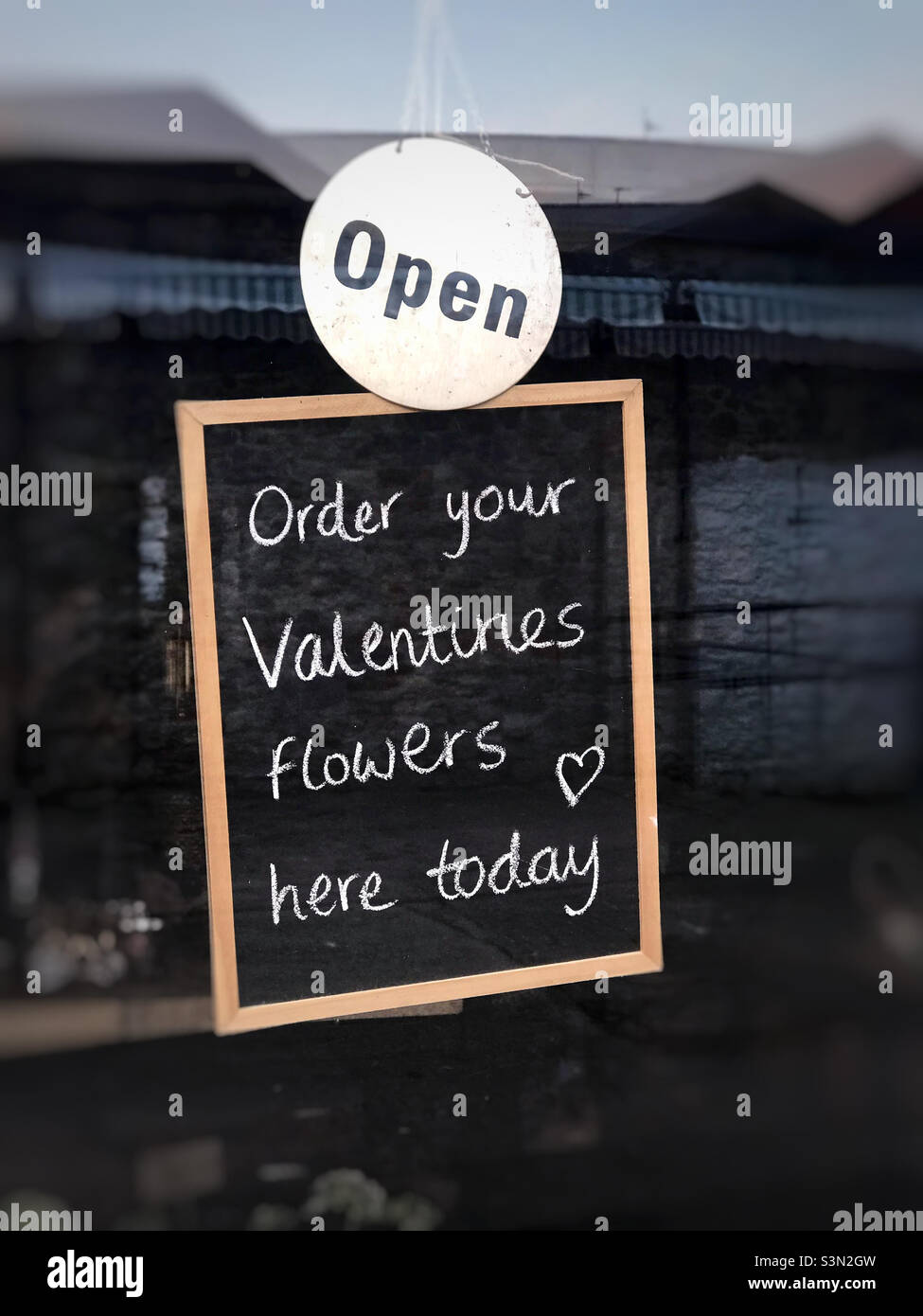 A sign in a flower shop suggesting you can buy your Valentines Day flowers from them. - Smartphone Captured Stock Image