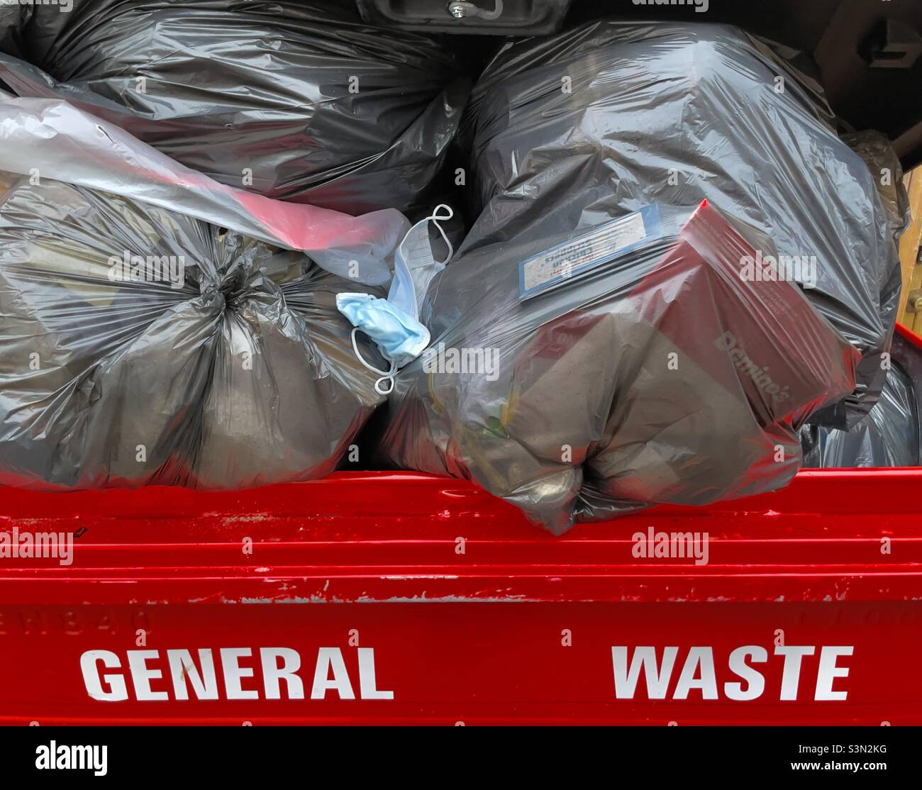 A wheelie bin in a Worcester alleyway containing plastic bags and a discarded facemask a symbol of the new freedom! - Smartphone Captured Stock Image