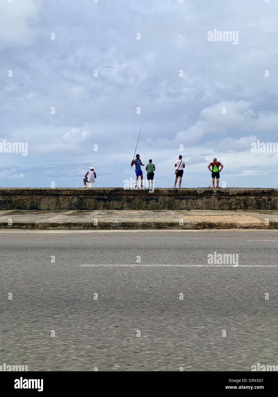 Man spending time together in Malecón, Havana, Cuba. One man fishing, four men watching. Leisure and relax. - Smartphone Captured Stock Image