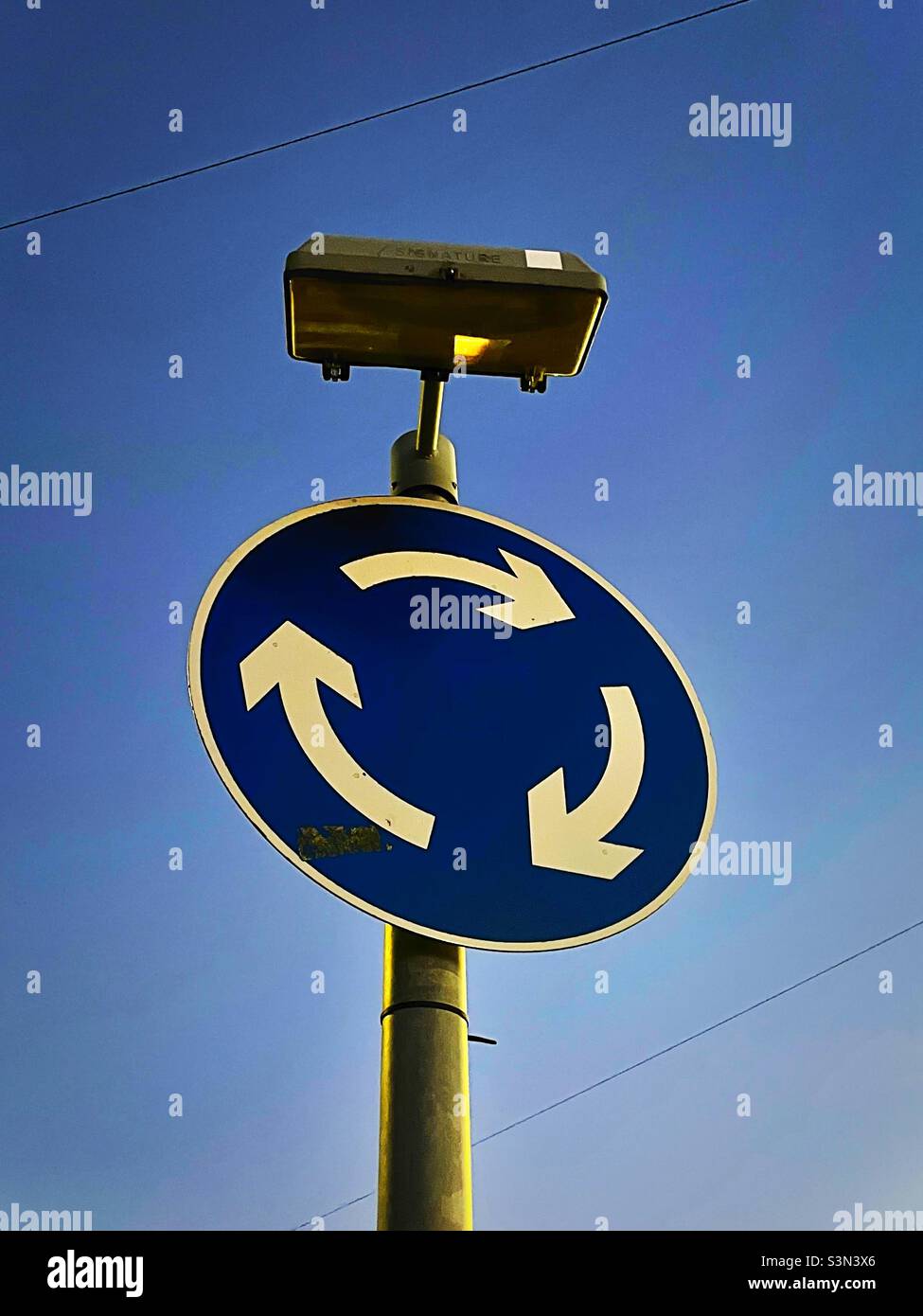 ‘Let’s go round again’ a road sign warns of the upcoming mini roundabout Stock Photo