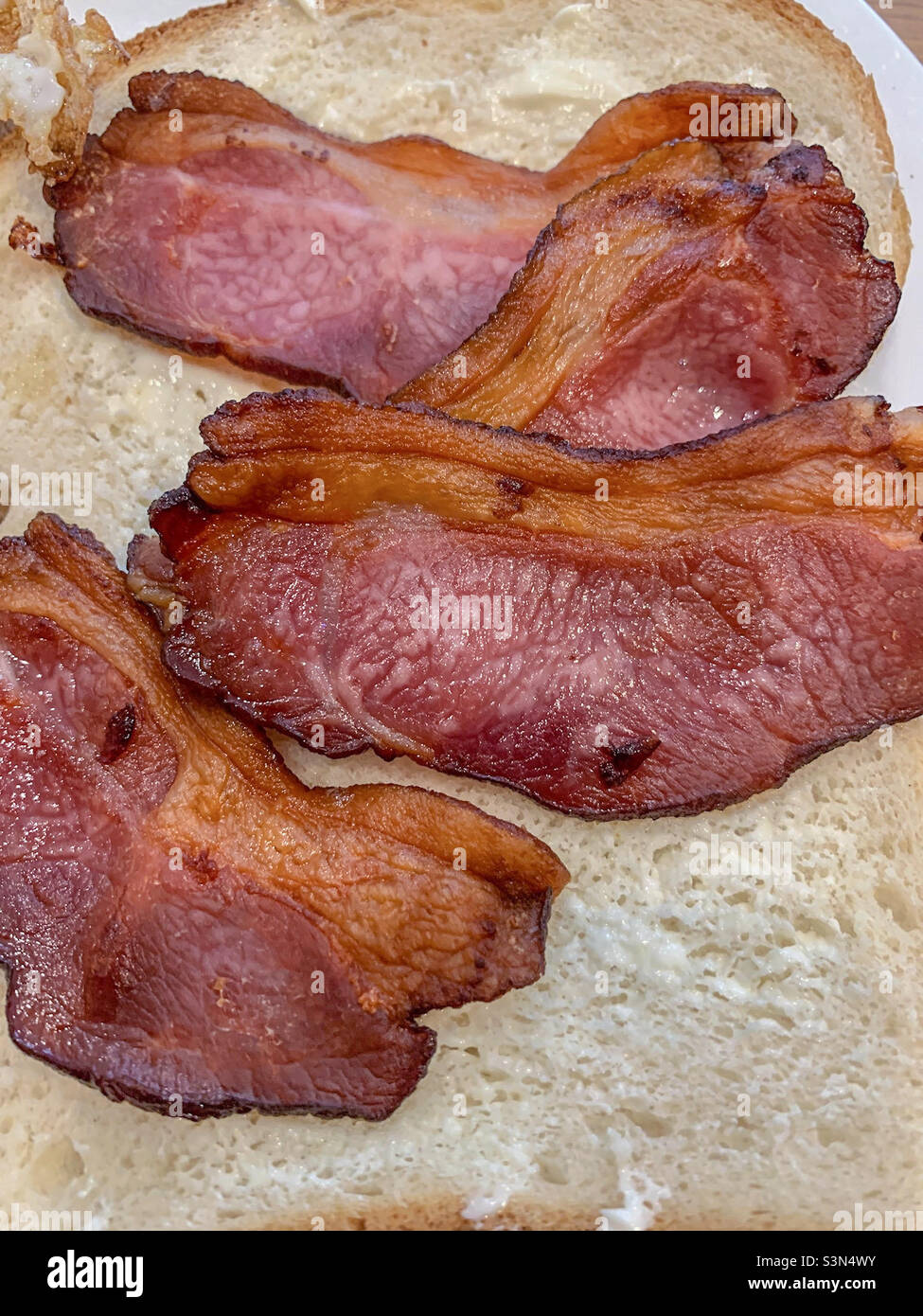 Well done bacon sandwich on white bread Stock Photo Alamy