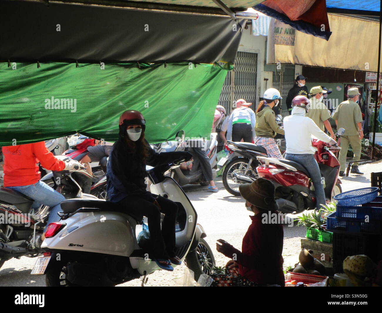 Police (in green shirt) inspect flower shops on Le Van Phan Street, Phu Thuy, Phan Thiet, Binh Thuan, Vietnam (29 January 2022 at 11h35) - Smartphone Captured Stock Image