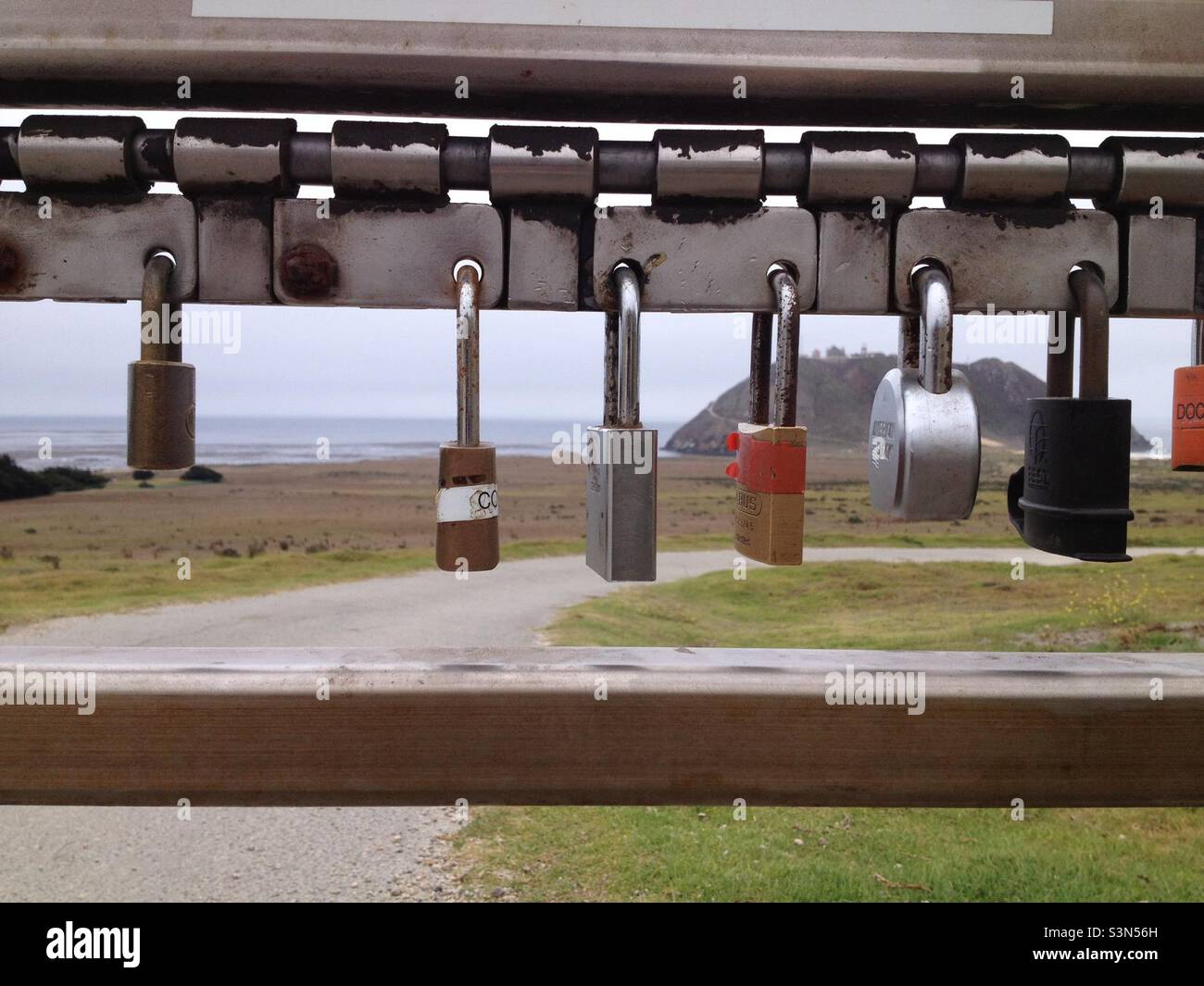 Close up of various love locks with Point Sur Lighthouse in the distance. - Smartphone Captured Stock Image