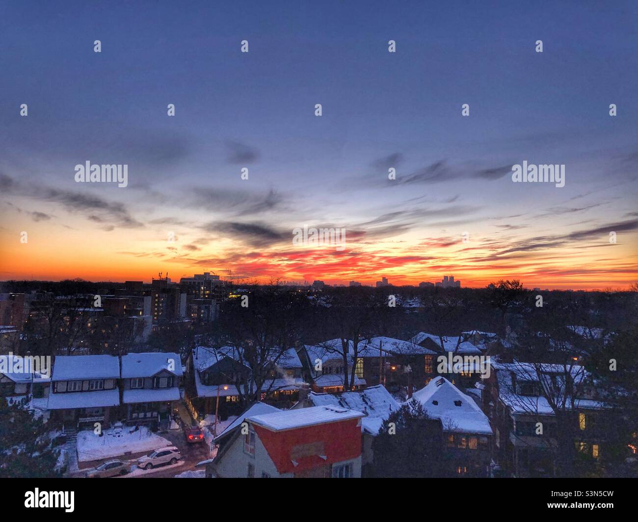 A sunset over snowy rooftops. Stock Photo