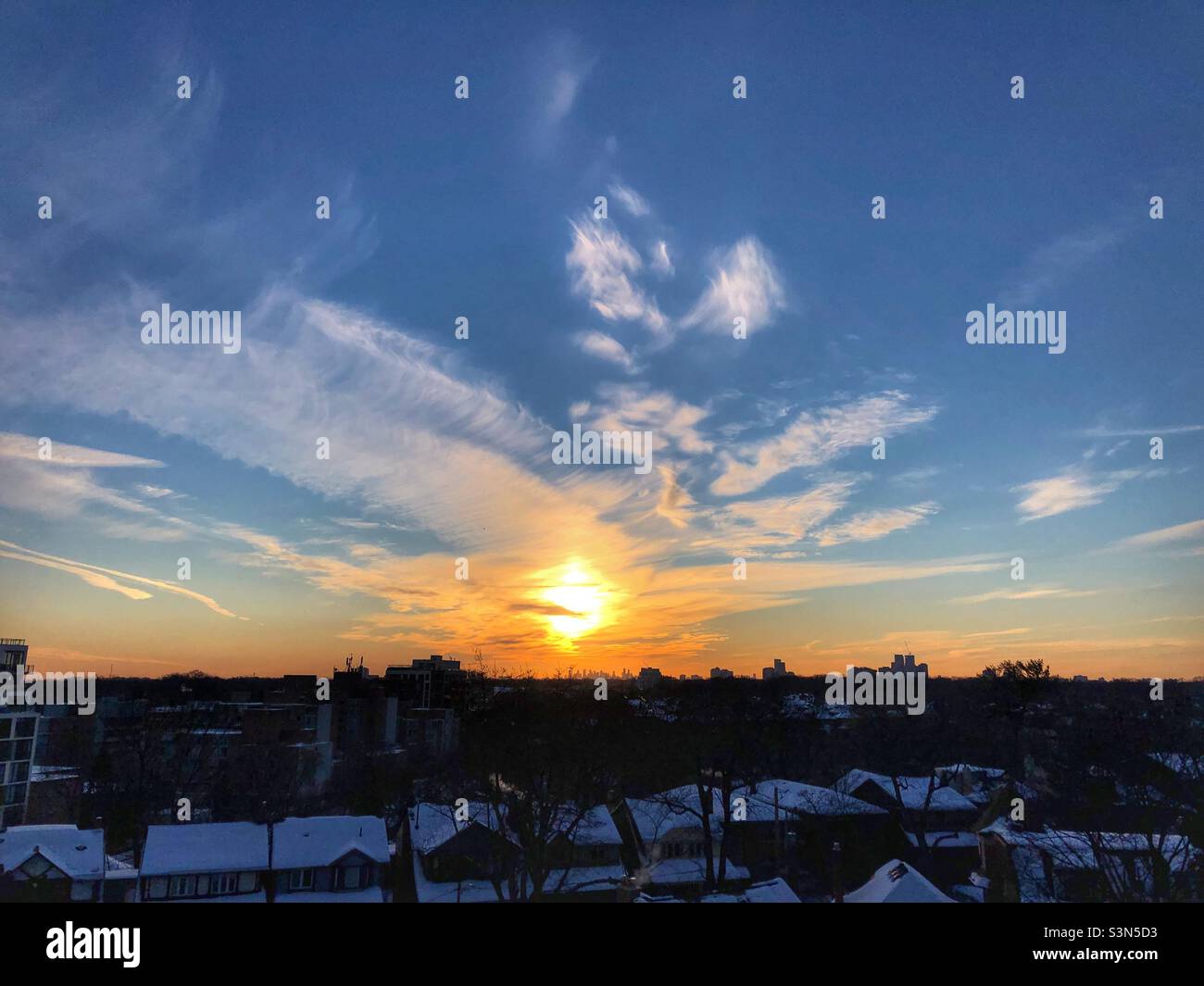 A warm sunset over snowy rooftops. Stock Photo