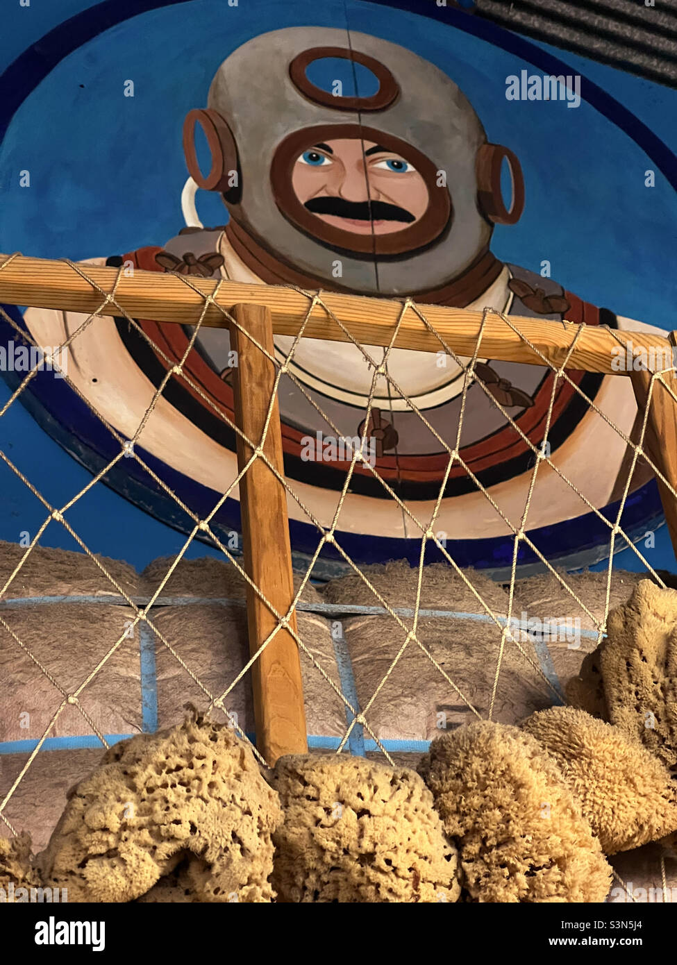 Sponge diver with old style diving suit and helmet mural with local Gulf of Mexico sponges in the foreground in Tarpon Springs, Florida. Stock Photo