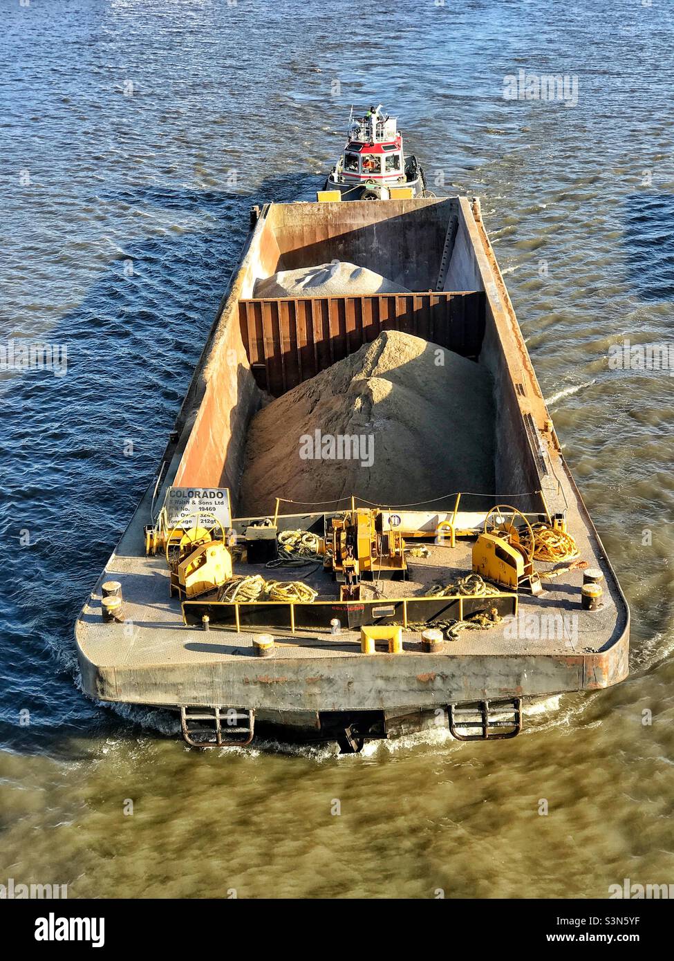 Container barge being transported by tugboat along the River Thames