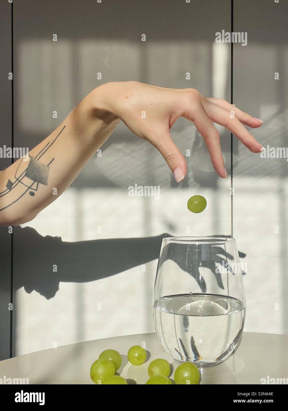 A green grape falling into the glass of water - Smartphone Captured Stock Image