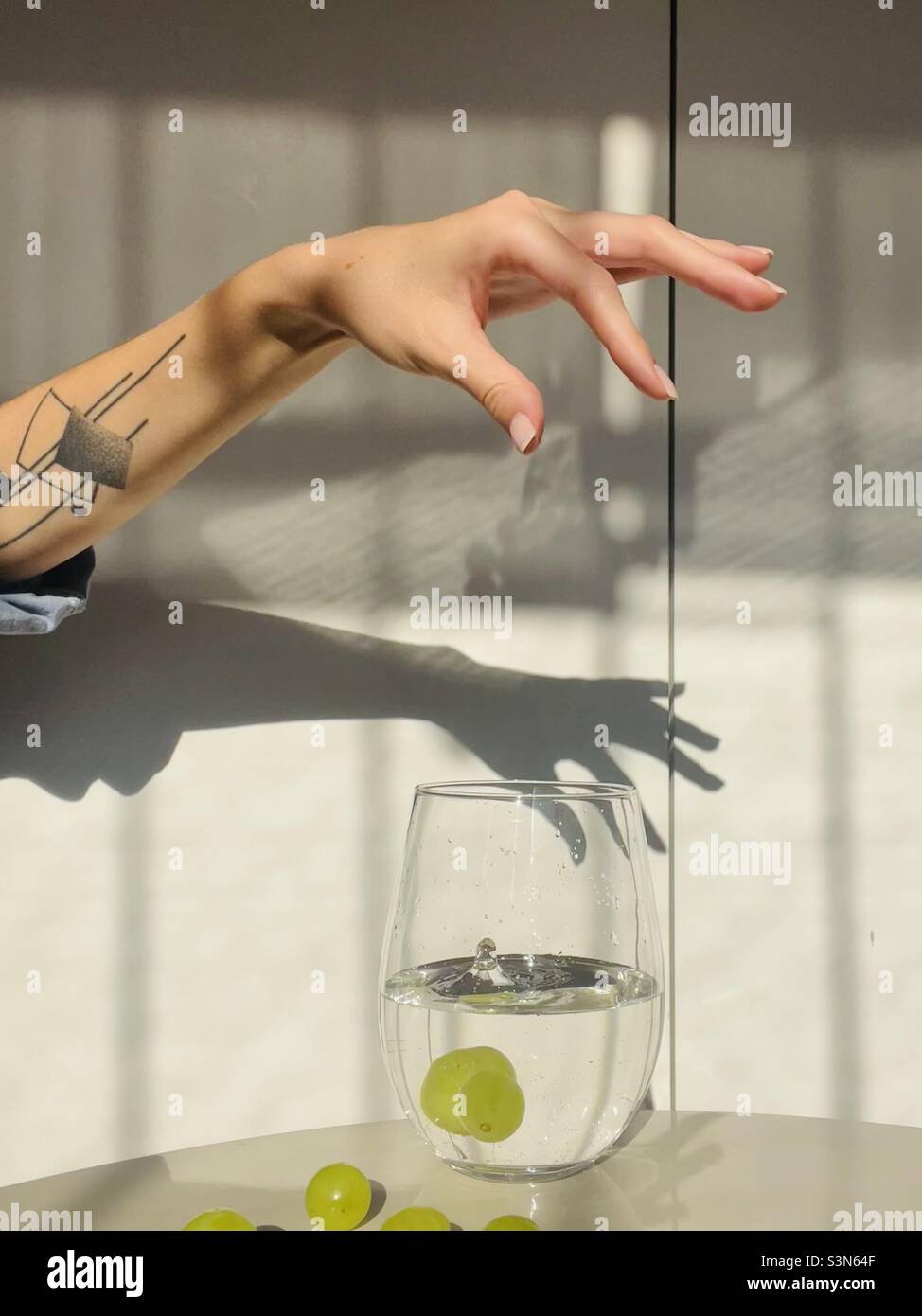 A green grape falling into the glass of water - Smartphone Captured Stock Image