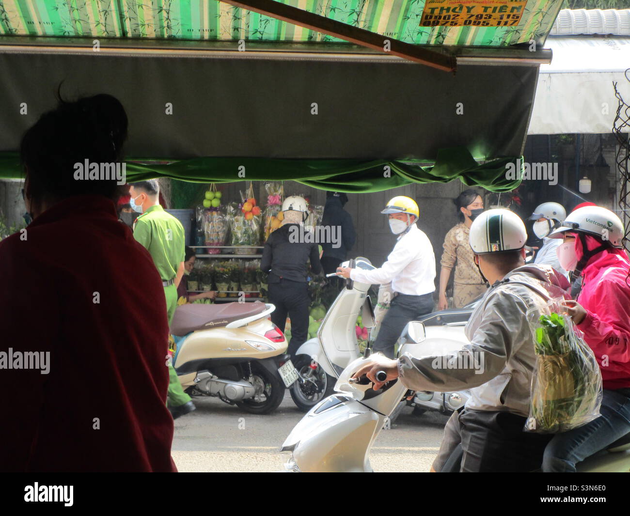 Police (in green shirt) inspect flower shops on Le Van Phan Street, Phu Thuy, Phan Thiet, Binh Thuan, Vietnam (29 January 2022 at 11h35) - Smartphone Captured Stock Image