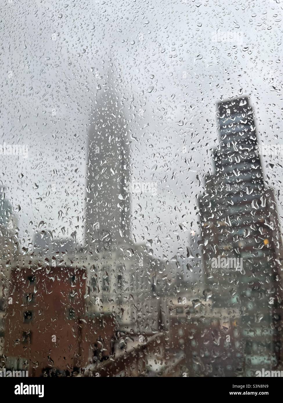 Empire State building shrouded in fog as viewed through a rain splattered window in New York City Stock Photo