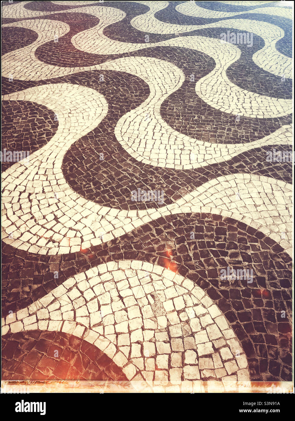 Retro effect image of an interesting swirling patterned walkway that uses thousands of small tiles to create a visually arresting design. Photo ©️ COLIN HOSKINS. - Smartphone Captured Stock Image