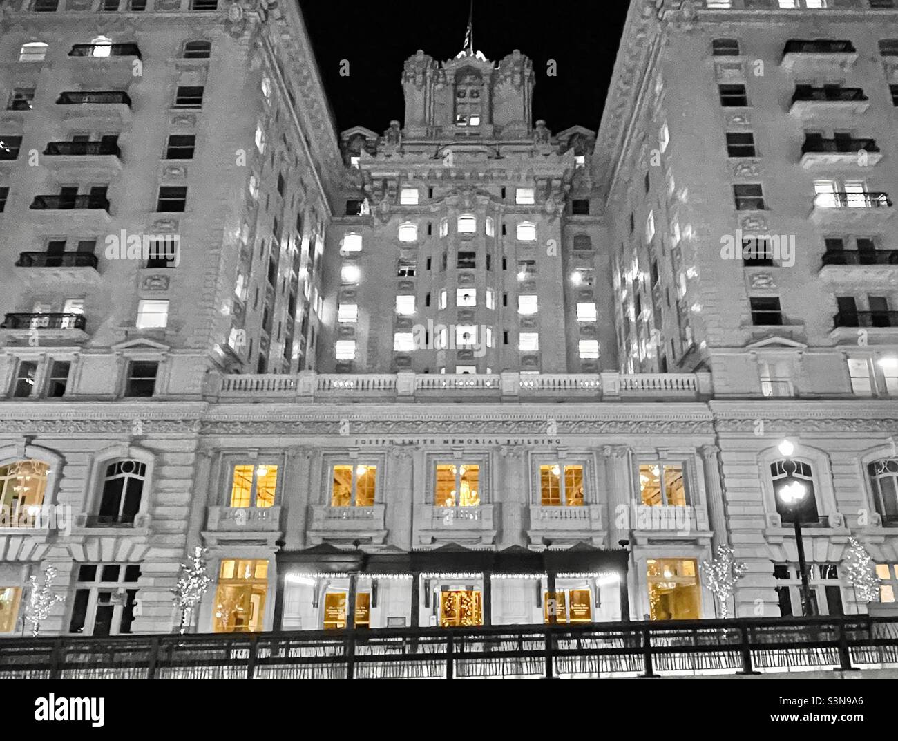 The Joseph Smith Memorial Building, or the former Hotel Utah, in downtown Salt Lake City, Utah, USA during the holidays. The building is desaturated except for the yellow light from the lower windows. - Smartphone Captured Stock Image