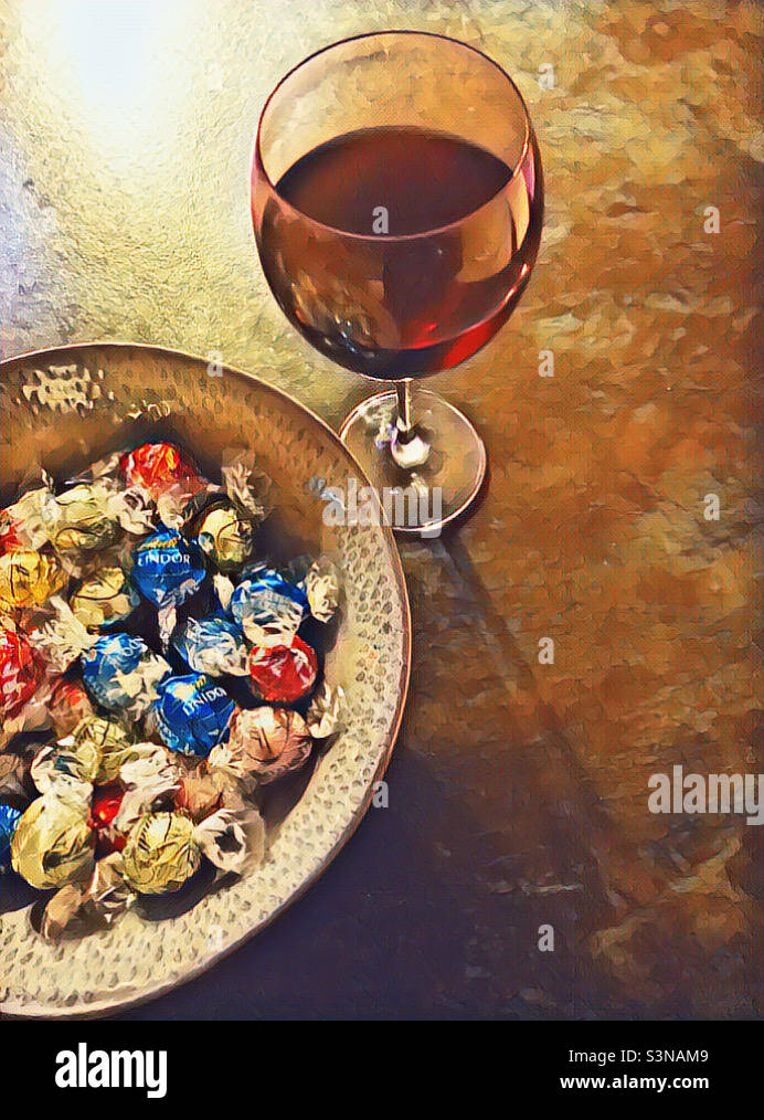 Weekend Treat - a glass of red wine and Lindt Lindor chocolate truffles. Picsart effect Stock Photo