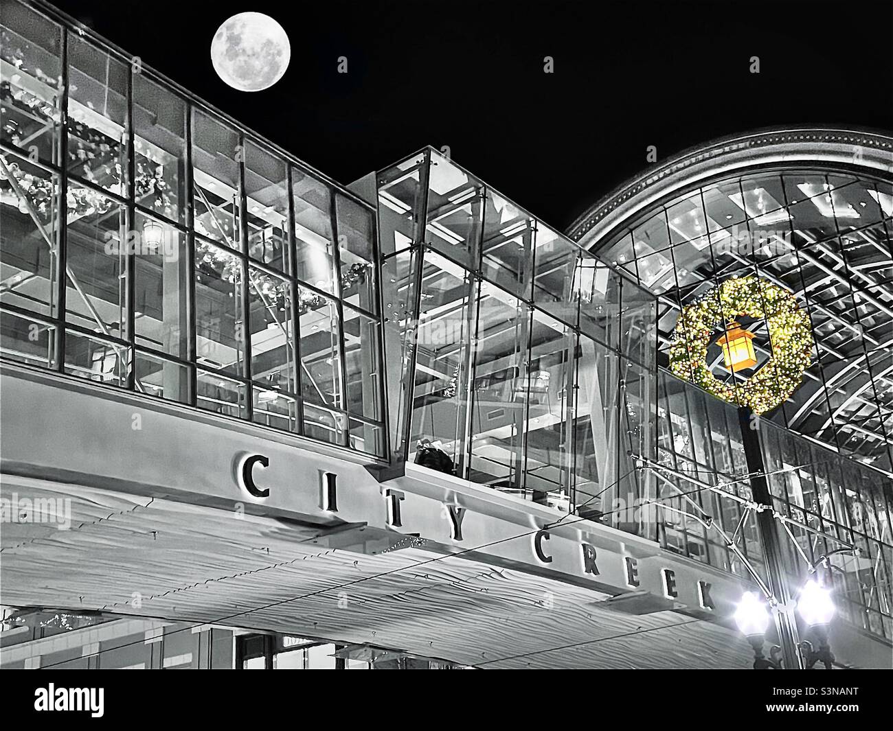 A view looking up at the City Creek Center bridge that crosses Main Street in Salt Lake City, Utah, USA. Black & white, except select color on the bigger than life wreath. Full moon digitally added. - Smartphone Captured Stock Image