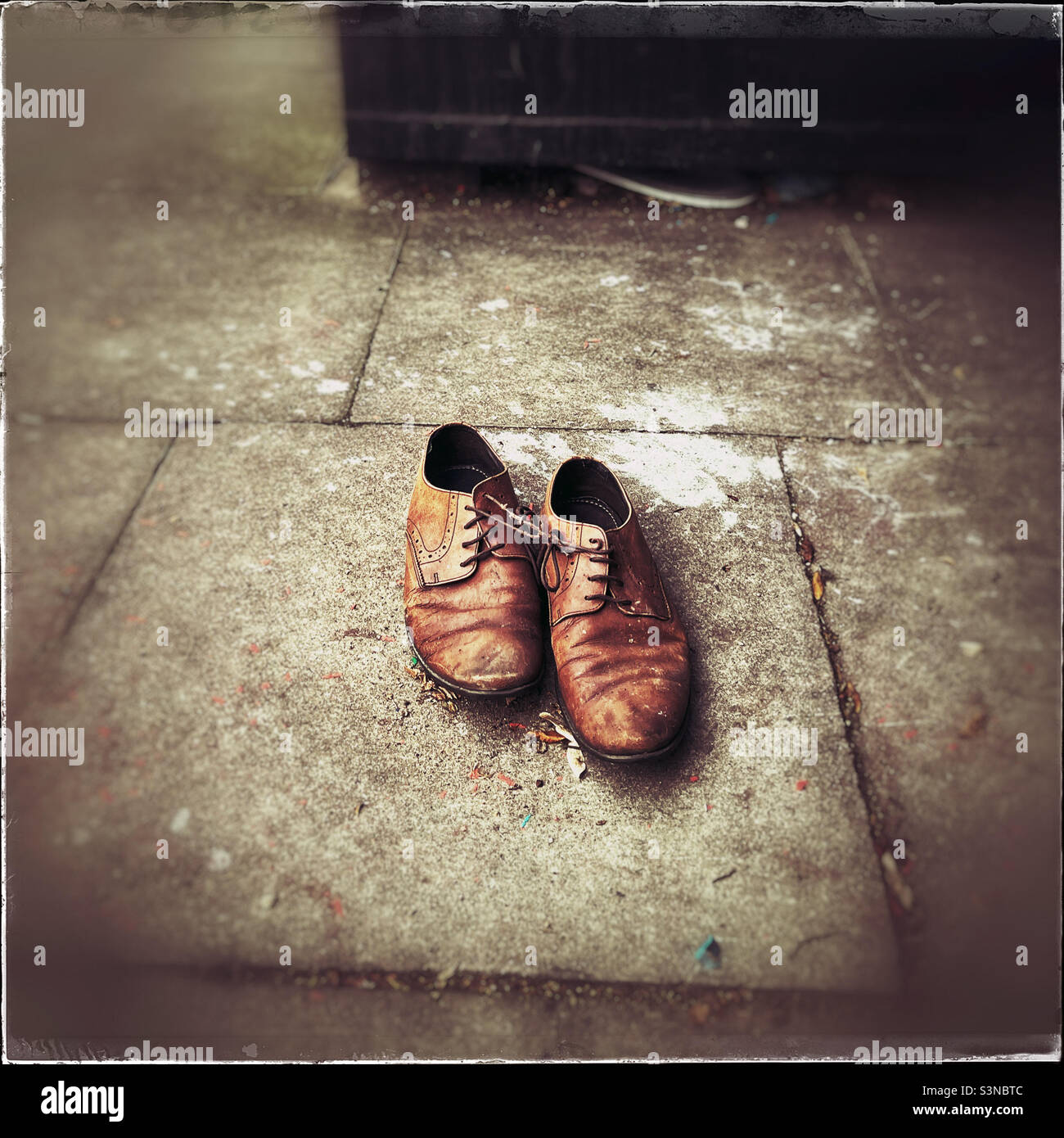 Old shoes left on pavement by clothes bank - Smartphone Captured Stock Image