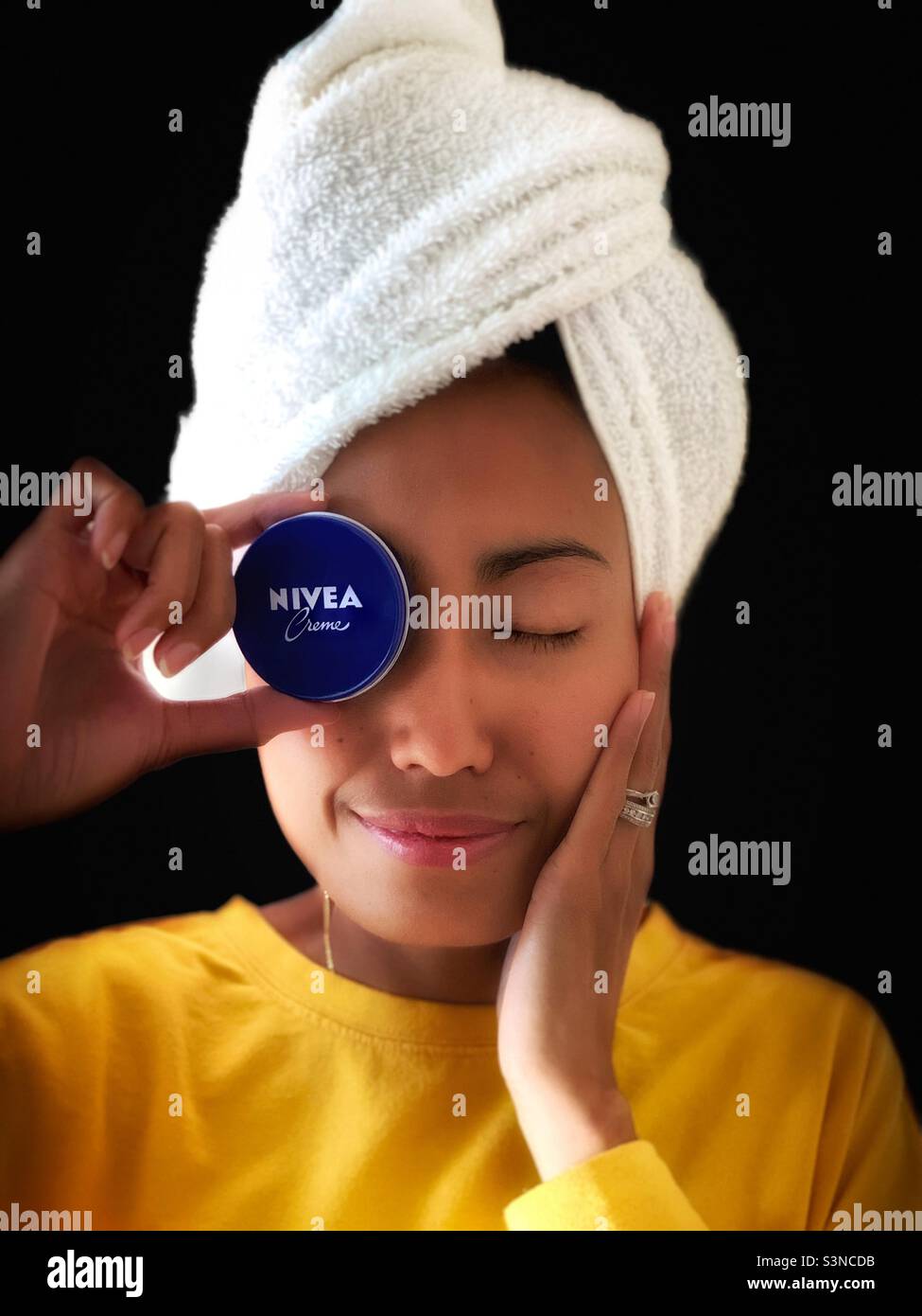 A woman holding a Nivea against black background - Smartphone Captured Stock Image