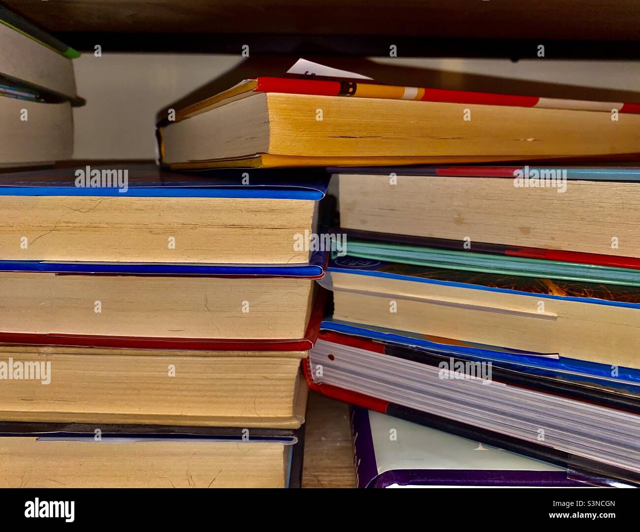 Stacks of dusty used books on a bookshelf, stained, neglected, forgotten, well read, concept of book banning, symbolism, banned, loved books, reading, writing, bookstore, book stack, library Stock Photo